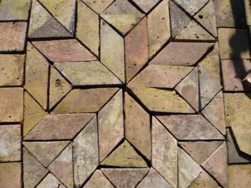 Interlocking geometric pavers forming a starburst pattern in tan, brown, and gray hues.