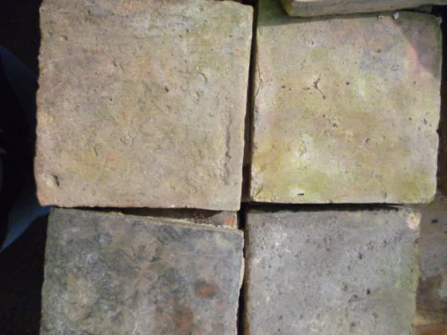 Four weathered concrete pavers arranged in a 2x2 grid, showing rough texture and earthy tones.