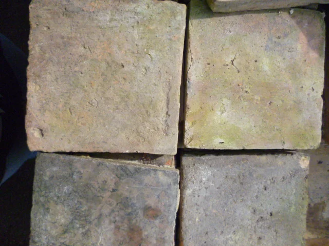 Four weathered concrete pavers arranged in a 2x2 grid, showing rough texture and earthy tones.